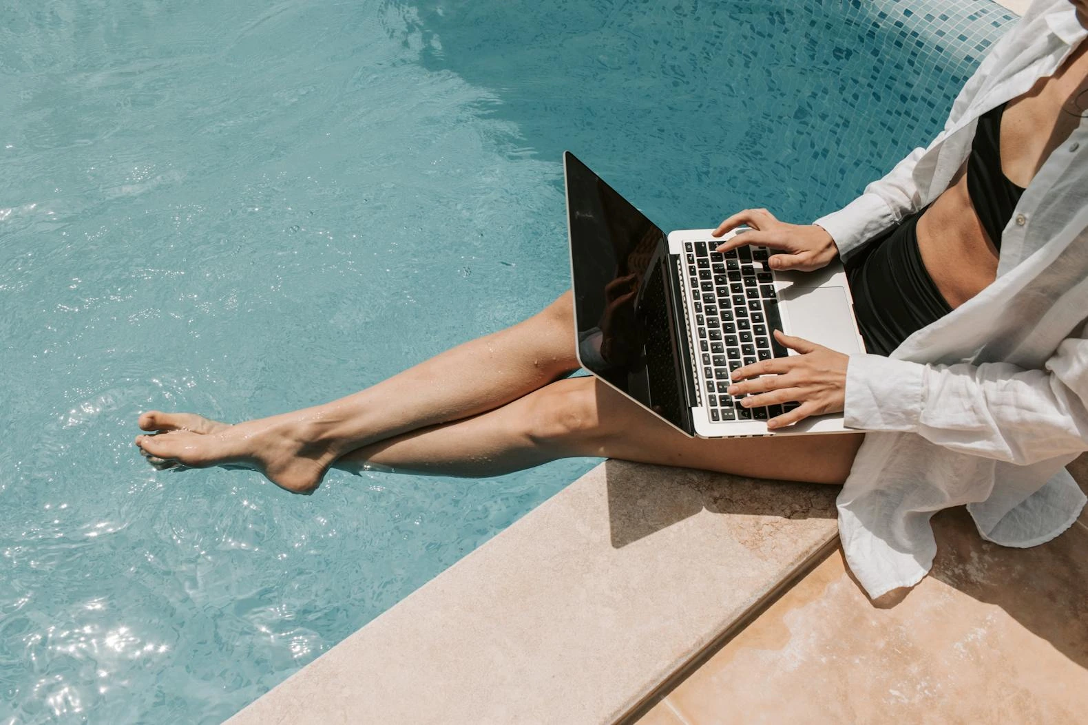 Woman with laptop by a pool. Photo by Vlada Karpovich via Pexels 